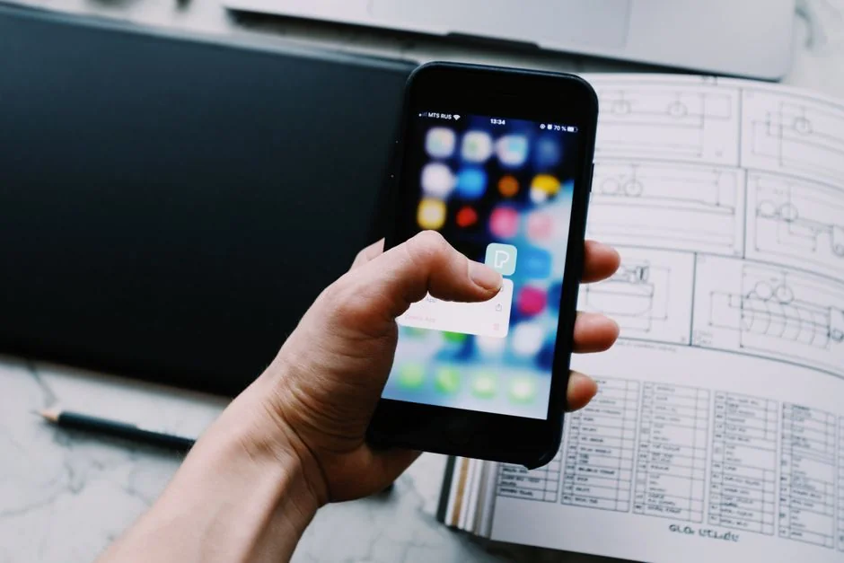 Vue rapprochée d’un smartphone affichant une image floue, posé sur un bureau à côté d’un ordinateur portable.